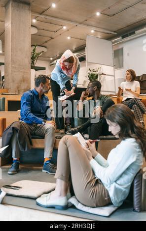 Focused, different aged coworkers discussing new project while working together at small amphitheater Stock Photo