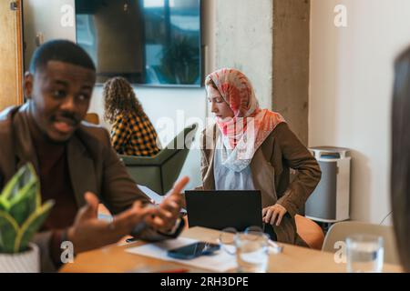 Muslim woman in hijab holding documents, preparing analyzing work results using lap top computer Stock Photo