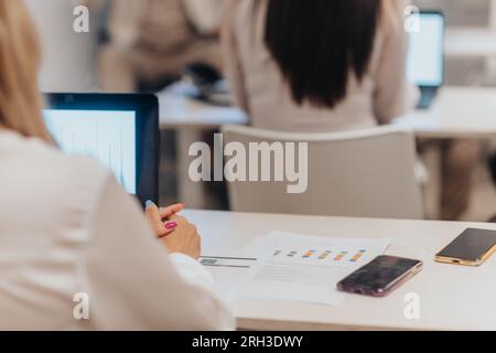 Businesswoman sitting at working desk and listening to economy presentation at the classroom. Back view, close up Stock Photo