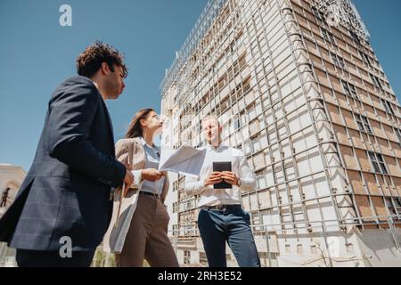 Woman architect explaining project to her male partners during meeting in the downtown area Stock Photo