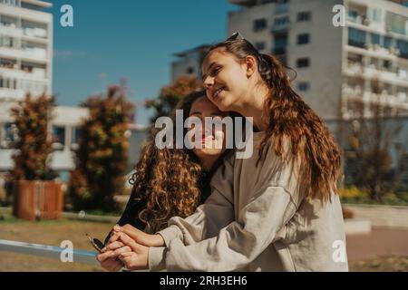 Two girls having deep conversation out in the park. They are hugging and comforting each other Stock Photo