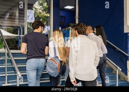 Back view photo of five students walking upstairs, going in college for a class Stock Photo