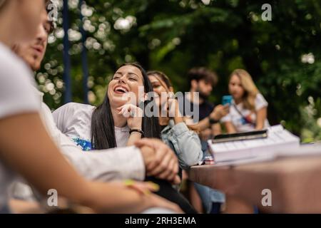 Positive, overjoyed university students sitting at table, having fun conversation and laughing after they finished studying Stock Photo