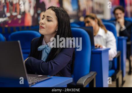 Female student working on her laptop with the other students while in class Stock Photo