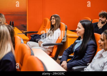 Students smiling and attending a lecture while in a lecture hall Stock Photo