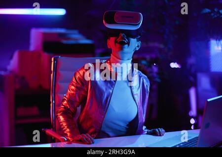Neon metaverse futuristic concept. excited stylish business woman in vr headset in modern office. Stock Photo