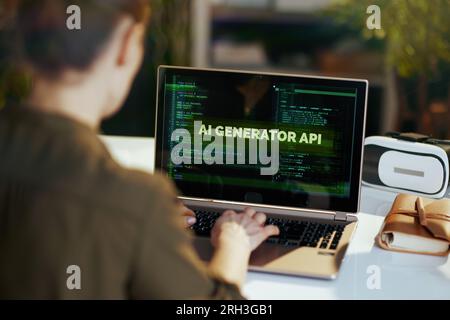 Seen from behind modern woman with laptop developing artificial intelligence software in modern office. Stock Photo