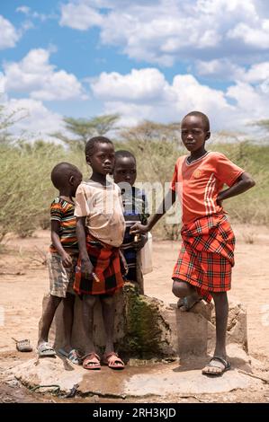 Young Kenyan boys stands by a water tap sourcing fresh water from a nearby bore hole, Baringo County, Kenya Stock Photo