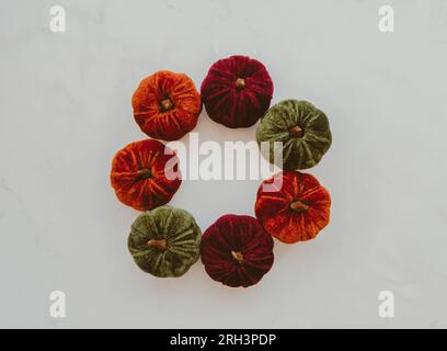 Round frame made of various colors velvet pumpkins on white background. Autumn, fall, Halloween concept. Flat lay, top view, copy space Stock Photo