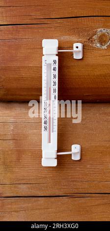 Thermometer on the wall of a wooden house. Weather thermometer  in degrees celsius. Stock Photo
