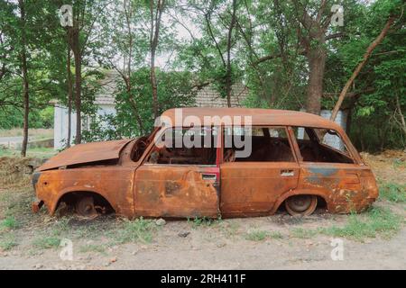 Countryside. On the side of the road is a destroyed, burned-out civilian car. War in Ukraine. Russian invasion of Ukraine. War crimes Stock Photo