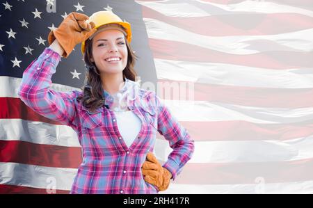 Female Contractor Wearing Blank Yellow Hardhat and Gloves Over Waving American Flag Background Banner. Stock Photo