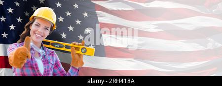 Female Contractor Wearing Blank Yellow Hardhat and Gloves Over Waving American Flag Background Banner. Stock Photo