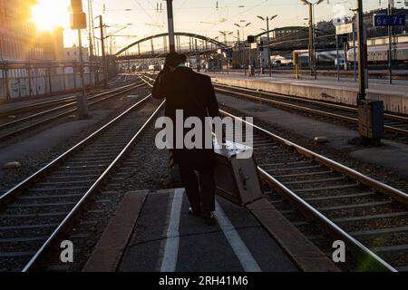 Man with suitcase walks to far end of platform station racks in early morning hours Stock Photo