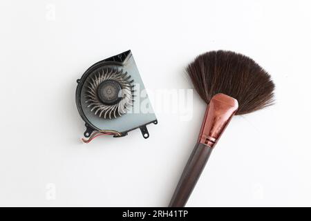 Cleaning brush and dusty laptop cooling fan on white background. Air vent fan for heatsink cooling system for cpu. Fixing overheating. Professional te Stock Photo