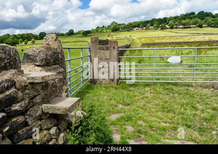 Stone steps forming a stile in a dry stone wall. The footpath leads up to Crook Farm Holiday Park from Shipley Glen in Baildon, West Yorkshire. Stock Photo