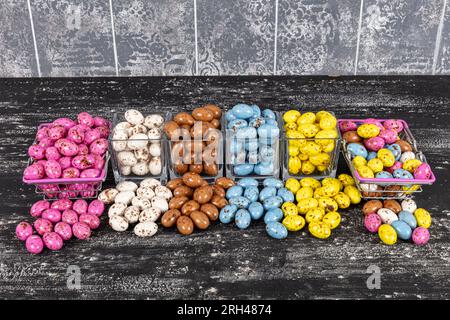 Heap of sugared almonds and hazelnuts dragees in chocolate isolated on dark background. Handmade colorful chocolate candies filled with nuts. Chocolat Stock Photo