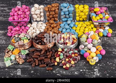 Heap of sugared almonds and hazelnuts dragees in chocolate isolated on dark background. Handmade colorful chocolate candies filled with nuts. Chocolat Stock Photo