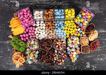 Heap of sugared almonds and hazelnuts dragees in chocolate isolated on dark background. Handmade colorful chocolate candies filled with nuts. Chocolat Stock Photo