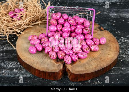 Heap of sugared almonds and hazelnuts dragees in chocolate isolated on dark background. Handmade colorful chocolate candies filled with nuts. Chocolat Stock Photo