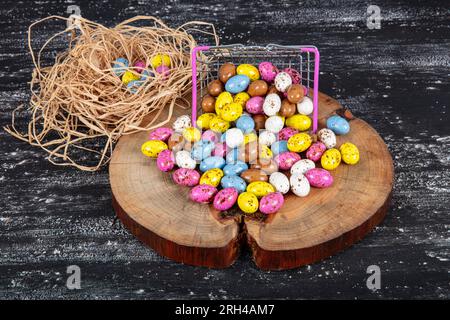 Heap of sugared almonds and hazelnuts dragees in chocolate isolated on dark background. Handmade colorful chocolate candies filled with nuts. Chocolat Stock Photo