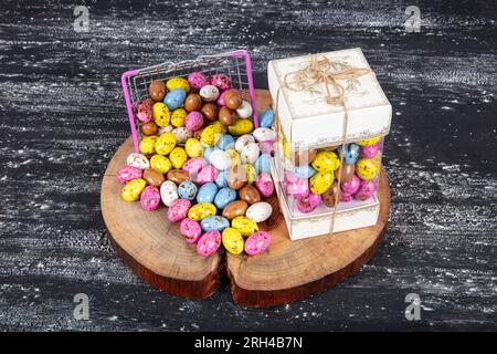 Heap of sugared almonds and hazelnuts dragees in chocolate isolated on dark background. Handmade colorful chocolate candies filled with nuts. Chocolat Stock Photo