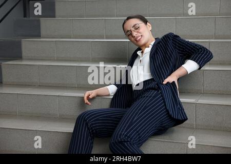 Woman fallen down stairs suffering from pain in back indoors Stock Photo