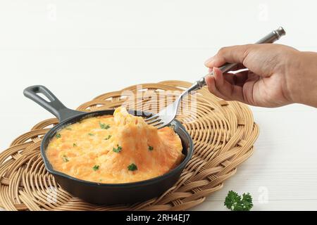 Female Hand Hold Fork to Eat Korean Baked Cheese on Skillet Pan Stock Photo