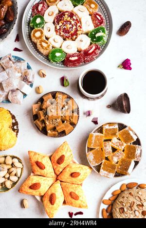 Middle Eastern Sweets, Turkish Delights and Black Coffee on white background. Arab dessert assortment, rahat lokum, halva, sherber, pismaniye with nut Stock Photo