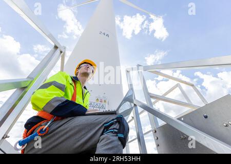 Engineer professional techician male working using laptop setup wind turbines system control operate service at location site Stock Photo