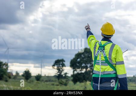 Engineer male working in wind turbines farm back view hand pointing at the sky for future of eco clean energy worker people Stock Photo