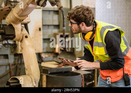 smart young engineer work service maintenace programming automatic robot welding machine in heavy metal automation factory Stock Photo