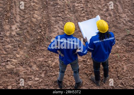 Land surveyor team standing working together at construction field consult study looking building location with floor plan Stock Photo