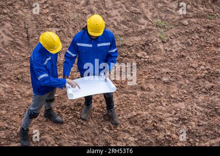 Land surveyor team standing working together at construction field consult study looking building location with floor plan Stock Photo