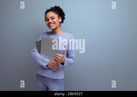 successful young afro brunette female student with a laptop and documents in her hands Stock Photo