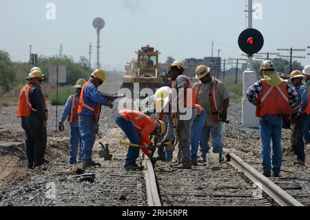 Railroad workers spike new track being laid down Stock Photo