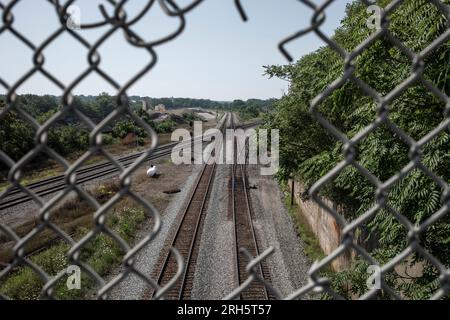 Overhead view of train tracks through hole in chain link fence Stock Photo