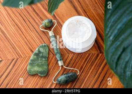 gouache roller, and stone with face cream on wooden background, top view. skin care concept Stock Photo
