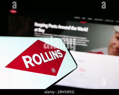Smartphone with logo of American pest control company Rollins Inc. on screen in front of business website. Focus on center-left of phone display. Stock Photo