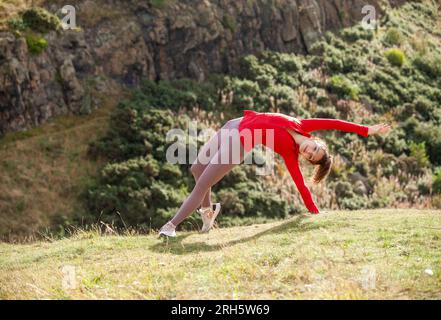 A young woman wearing leggings stretching in a public park in Edinburgh Stock Photo