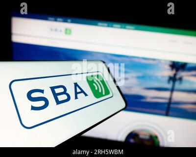 Smartphone with logo of American company SBA Communications Corporation on screen in front of business website. Focus on left of phone display. Stock Photo