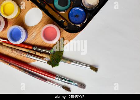 Flat lay of colorful paints, painting palette and brushes on white background, art, painting and hobby concept, top view, copy space. Stock Photo
