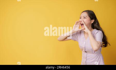 Woman teen standing big shout out with hands next mouth giving excited positive, present and call on orange background Stock Photo