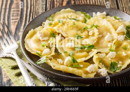Ravioli mezzaluna pasta with goat cheese and herbs close-up in a plate on the table. Horizontal Stock Photo