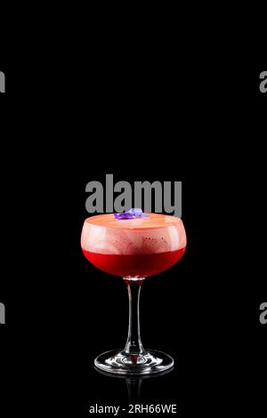 Fruity frozen strawberry margarita cocktail with violet flower isolated on a black background. Fresh alcoholic cocktail. Stock Photo