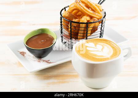 Cup of cappuccino with freshly dessert and chocolate syrup on white wooden background. Breakfast concept. Stock Photo