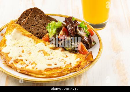 Omelette with cheese, tomatoes and green with orange juce on wooden background. Tasty freshly breakfast. Stock Photo