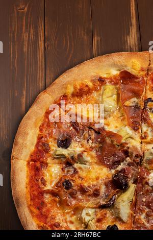 Pizza with tomato sauce, mixed cheese selection, ham, pepperoni, bacon, fresh mushrooms and olives. Stock Photo