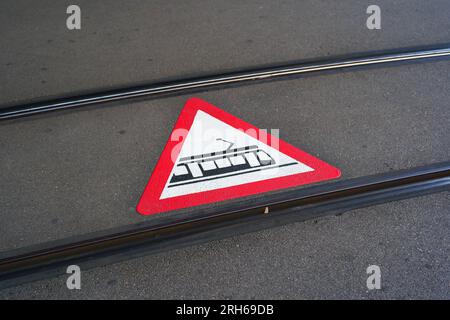 Tram crossing warning sign or pictogram painted on the asphalt road between train tracks in a city in Europe. No people. Stock Photo