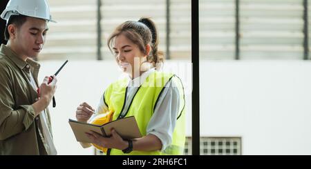 Young architect and engineer colleague workers working discussion, meeting and analyzing blueprint at construction site Stock Photo